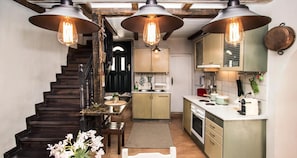 A kitchen with wooden stairs, a dining table, and pendant lights.