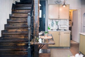 Eine Treppe führt zu einer Küche mit Holzausstattung, einem Spülbecken und einer Pendelleuchte.