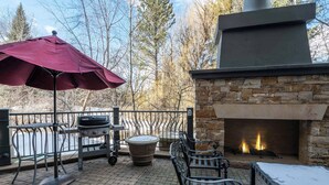 Eine Außenpatio mit Kamin aus Stein, Grill und Bank.