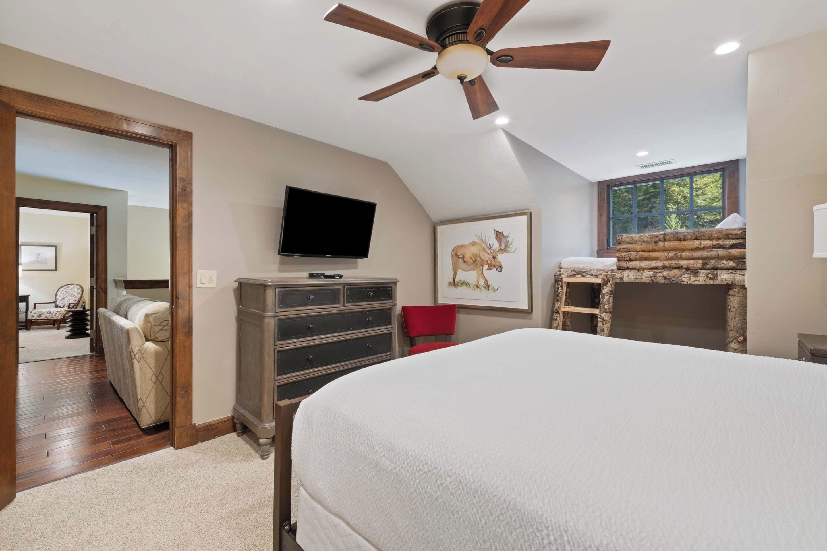 Ein Schlafzimmer mit Bett, Fernseher, Kamin und Deckenventilator.
