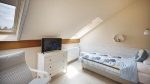 A bedroom with a bed, a TV on a dresser, a window, and a lamp on the wall. - TópART Apartman I: Apartment with terrace (Balatonfenyves)