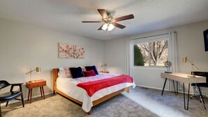 Ein Schlafzimmer mit Bett, Schreibtisch, Stuhl, Deckenventilator und Fenster.