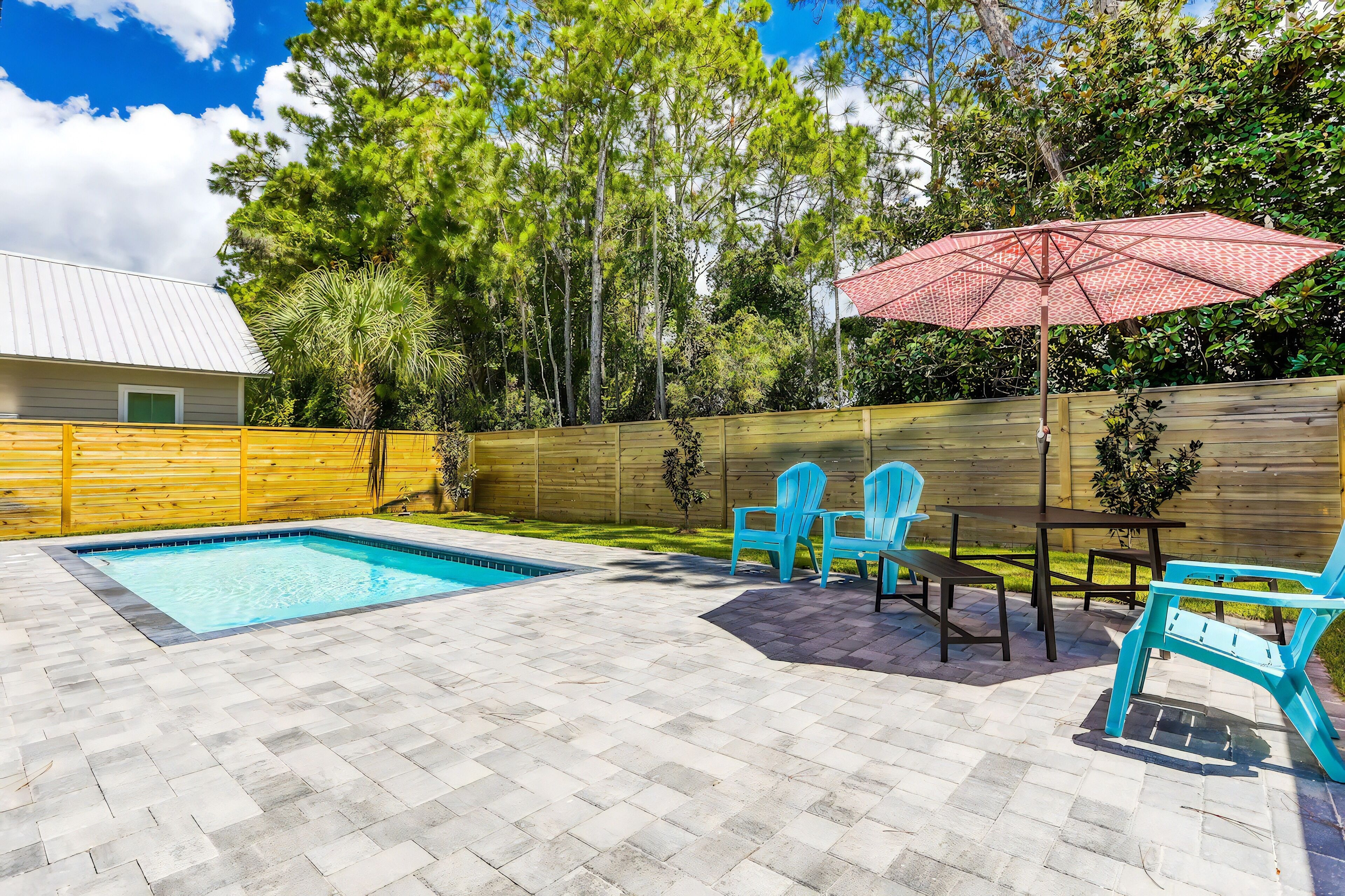 A backyard with a swimming pool, patio furniture, and a wooden fence.
