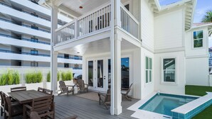 Une terrasse extérieure à plusieurs niveaux, dotée d’une piscine, de mobilier en bois et offrant une vue sur un immeuble de grande hauteur.