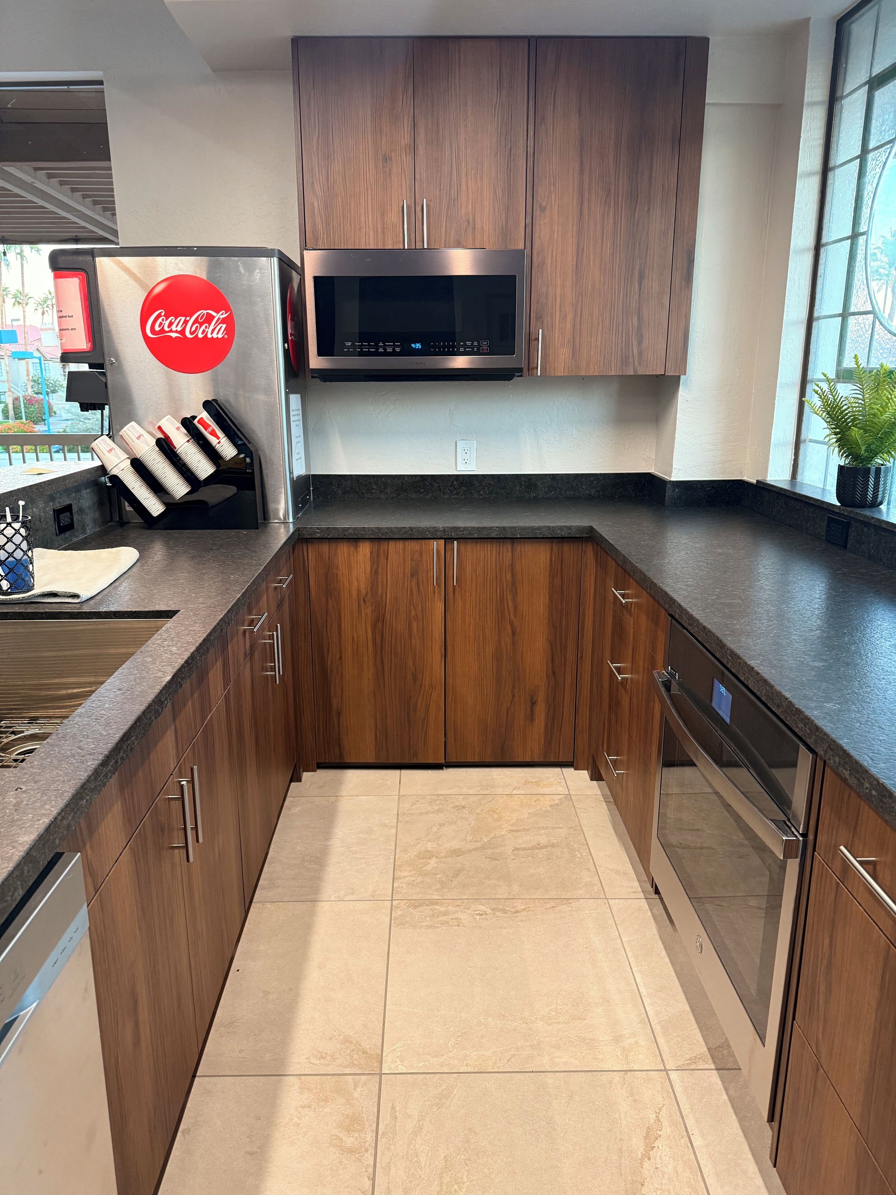 Een moderne keuken met houten kastjes, een roestvrijstalen koelkast, een magnetron en een vaatwasser.