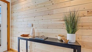Un mur en bois sur lequel est posée une console noire, ornée d’une plante, d’un bol et d’un objet décoratif.