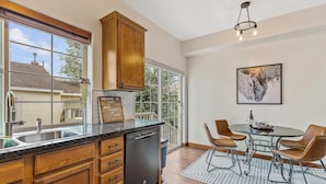 A modern kitchen with wooden cabinets, a dishwasher, and a large window. - NAU/DT | Elevated 2 bdrm | AC | Dog Friendly (Flagstaff)