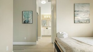 Een slaapkamer met een bed, een gang naar een badkamer en uitzicht op de badkamer.