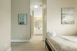 Une chambre avec un lit, un couloir menant à une salle de bain, et une vue sur la salle de bain.