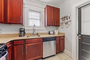A kitchen with wooden cabinets, a dishwasher, a coffee maker, and a toaster. - The Home Collection: Pet Friendly Dilworth 2BR w/ Balcony near Atrium CMC (Charlotte)