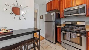 Una cocina con armarios de madera, un refrigerador de acero inoxidable, un microondas y una estufa a gas.