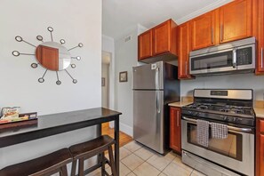 A kitchen with wooden cabinets, a stainless steel refrigerator, a microwave, and a gas stove. - The Home Collection: Pet Friendly Dilworth 2BR w/ Balcony near Atrium CMC (Charlotte)