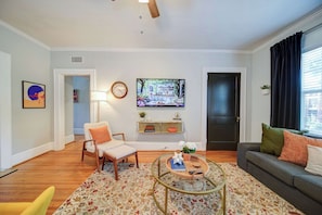 Un salon comprenant un canapé, un fauteuil, une table basse, un téléviseur et une porte.