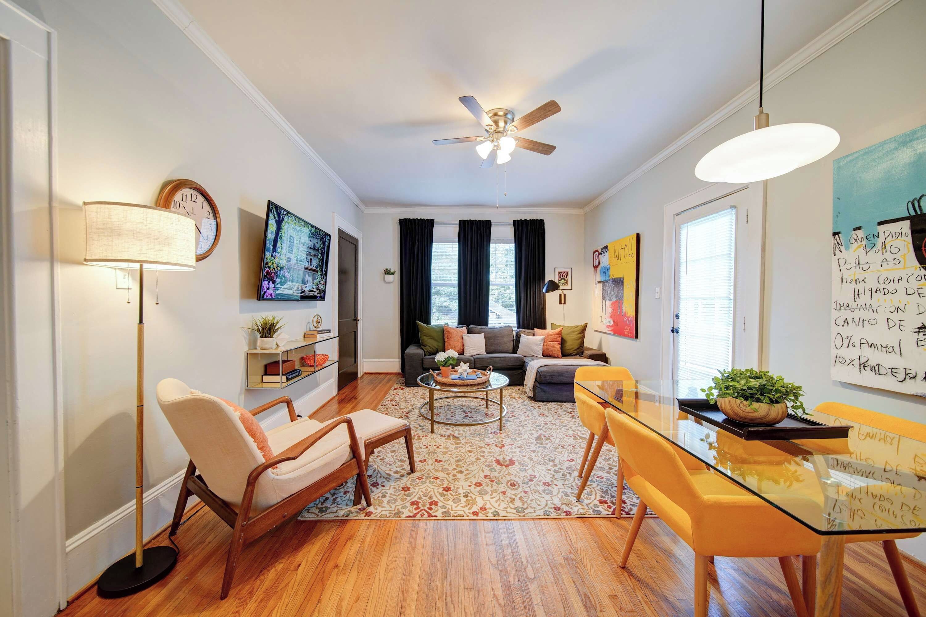 Uma sala de estar moderna com ventilador de teto, sofá, mesa de centro e mesa de jantar com cadeiras.