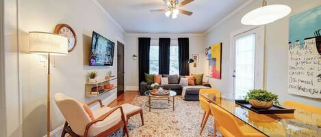 Uma sala de estar moderna com ventilador de teto, sofá, mesa de centro e mesa de jantar com cadeiras.