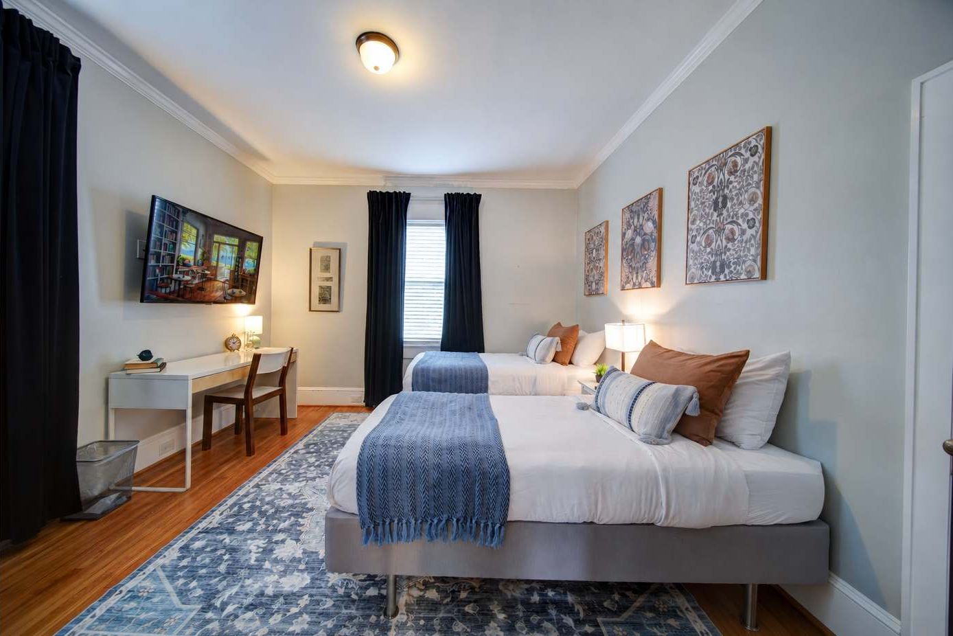 Bright twin bedroom with two comfortable beds, fresh linens, Smart TV, and a dedicated workspace for working or studying during your stay.
