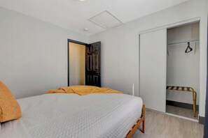 A bedroom with a bed, a wardrobe, and a door leading to a bathroom. - Amazing 4BD Home w/Pool, Arcades, & Billiard! (Las Vegas)