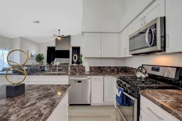 A modern kitchen with white cabinetry, a stainless steel microwave, a gas stove, and a dishwasher.
