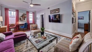A living room with a sofa, armchair, coffee table, and television.