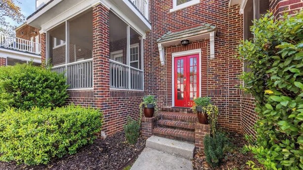 A brick house with a red door, a covered porch, and a small front yard with plants. - The Home Collection: Historic Step-Free 2BR, Pet Friendly & Close to  Atrium CMC (Charlotte)
