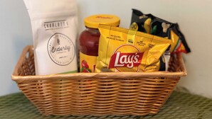 A wicker basket containing a jar of honey, a bag of Lay's potato chips, and a bottle of Charlotte's real honey. - The Home Collection: Historic Step-Free 2BR, Pet Friendly & Close to  Atrium CMC (Charlotte)