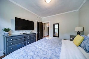 Un dormitorio con cama, cómoda, televisor y espejo.