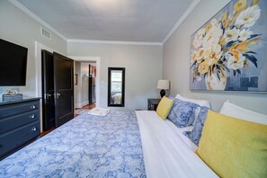 Een slaapkamer met een bed, een dressoir, een televisie en een schilderij.