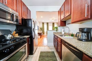 Une cuisine moderne avec des meubles en bois, un réfrigérateur en acier inoxydable, une cuisinière et une machine à café.