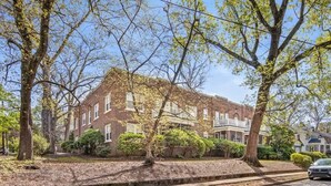 A two-story brick building with a front porch and a driveway.