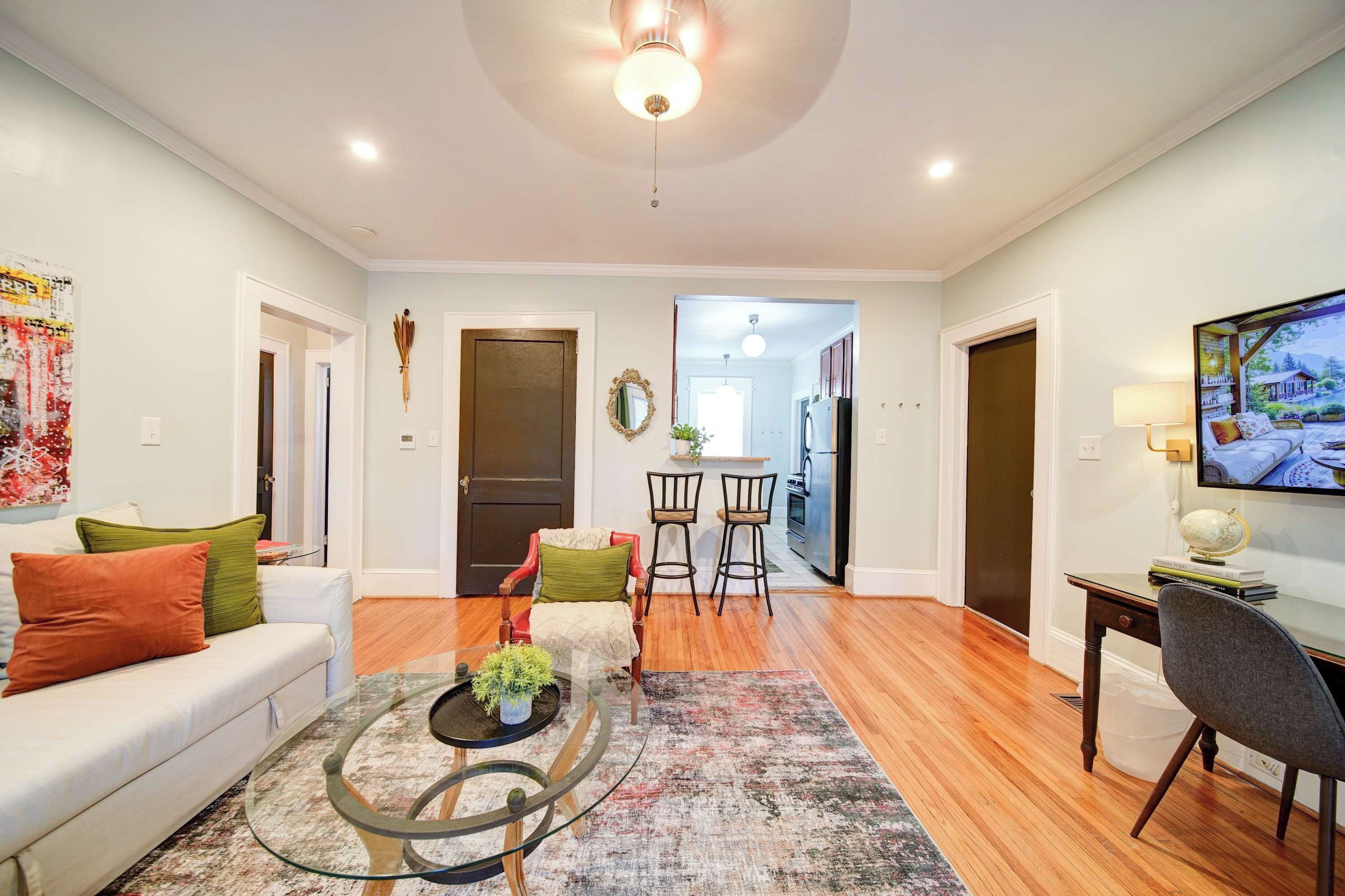A spacious living room with a sofa, coffee table, and a TV on a stand.
