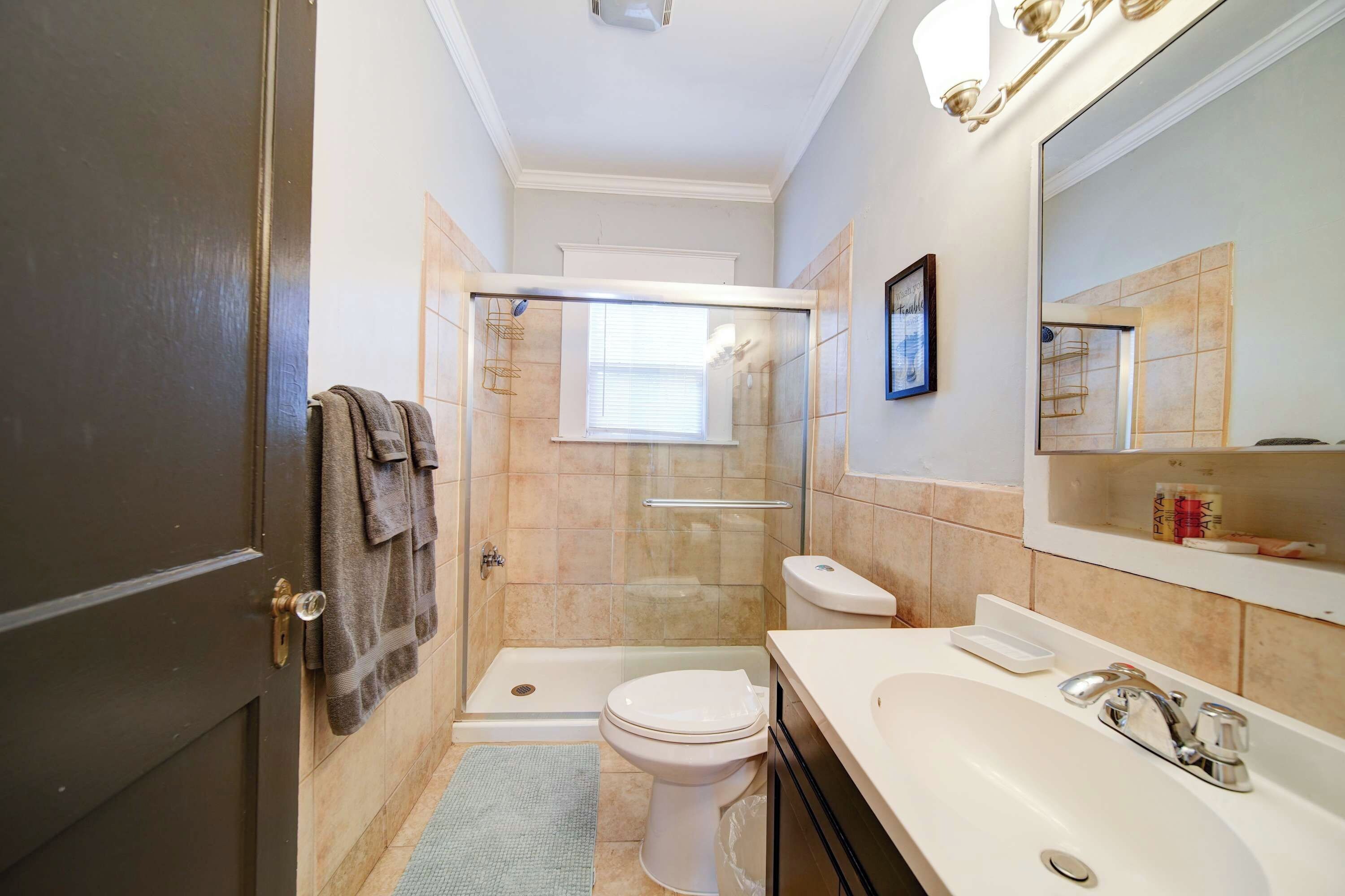 Un bagno con doccia, WC, lavandino e specchio.