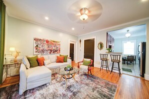 A modern living room with a sofa, chairs, a coffee table, and a painting on the wall. - The Home Collection: Pet-Friendly King Suite near South End & Freedom Park (Charlotte)
