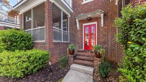 A two-story brick building with a red door and a covered porch.