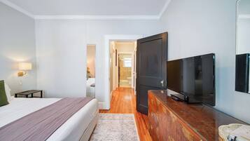 Ein Hotelzimmer mit einem Bett, einem Fernseher, einer Kommode und einem durchgegangenen Tür sichtbaren Badezimmer.