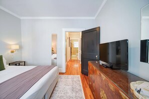 Une chambre d’hôtel avec un lit, une télévision, une commode et une salle de bain visible à travers une porte ouverte.