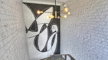 A staircase with a modern light fixture and a large abstract mural on the wall.