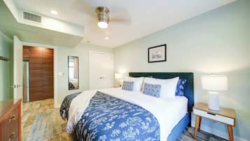 A bedroom with a bed, bedside lamps, a nightstand, a dresser, a door, and a ceiling vent.