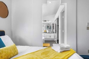 A hotel room with a bed, a bathroom visible through an open door, and a mirror.