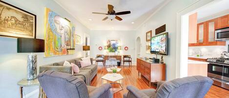 A living room with a sofa, two armchairs, a coffee table, and a dining area with a table and chairs.