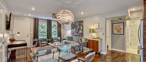 A modern living room with a glass coffee table, a sofa, and a dining area with a glass table.