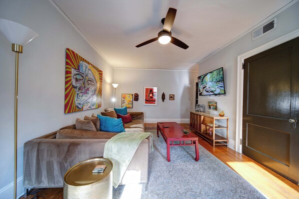 A living room with a sofa, a coffee table, a television, and artwork on the walls.
