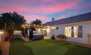 A house with a patio, a hot tub, and a well-maintained lawn.