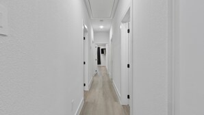 A narrow, white-walled hallway with a wooden floor and white doors on both sides. - Spacious ,Luxury 3-bedroom apartment in Houston with Games ,Smart Tv,Wifi (Houston)