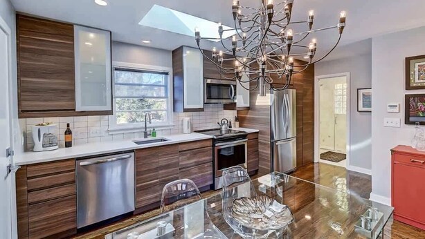 Une cuisine moderne avec des meubles en bois, des appareils électroménagers en acier inoxydable et une table à manger en verre.