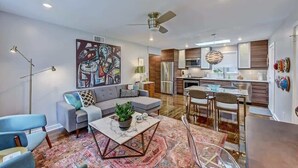 Un salon moderne comprenant un canapé, une table basse et un coin repas avec des chaises.