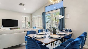 A dining area with a wooden table set for four, blue upholstered chairs, and a modern chandelier.