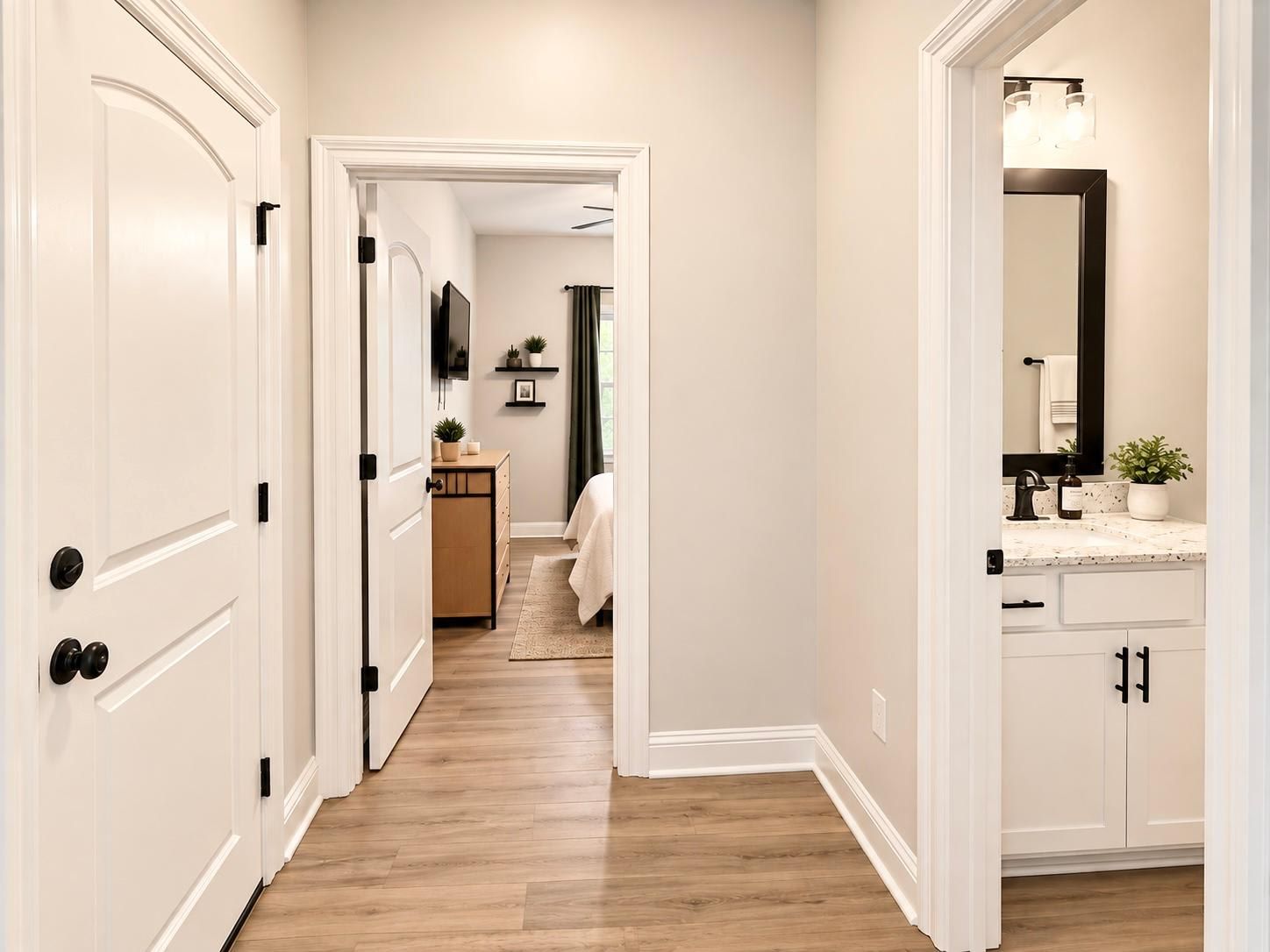 A hallway with white doors, a wooden floor, and a bathroom with a mirror, sink, and towel rack.