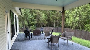 Una terrazza esterna con pavimento in pietra, una ventola a soffitto e mobili in vimini.