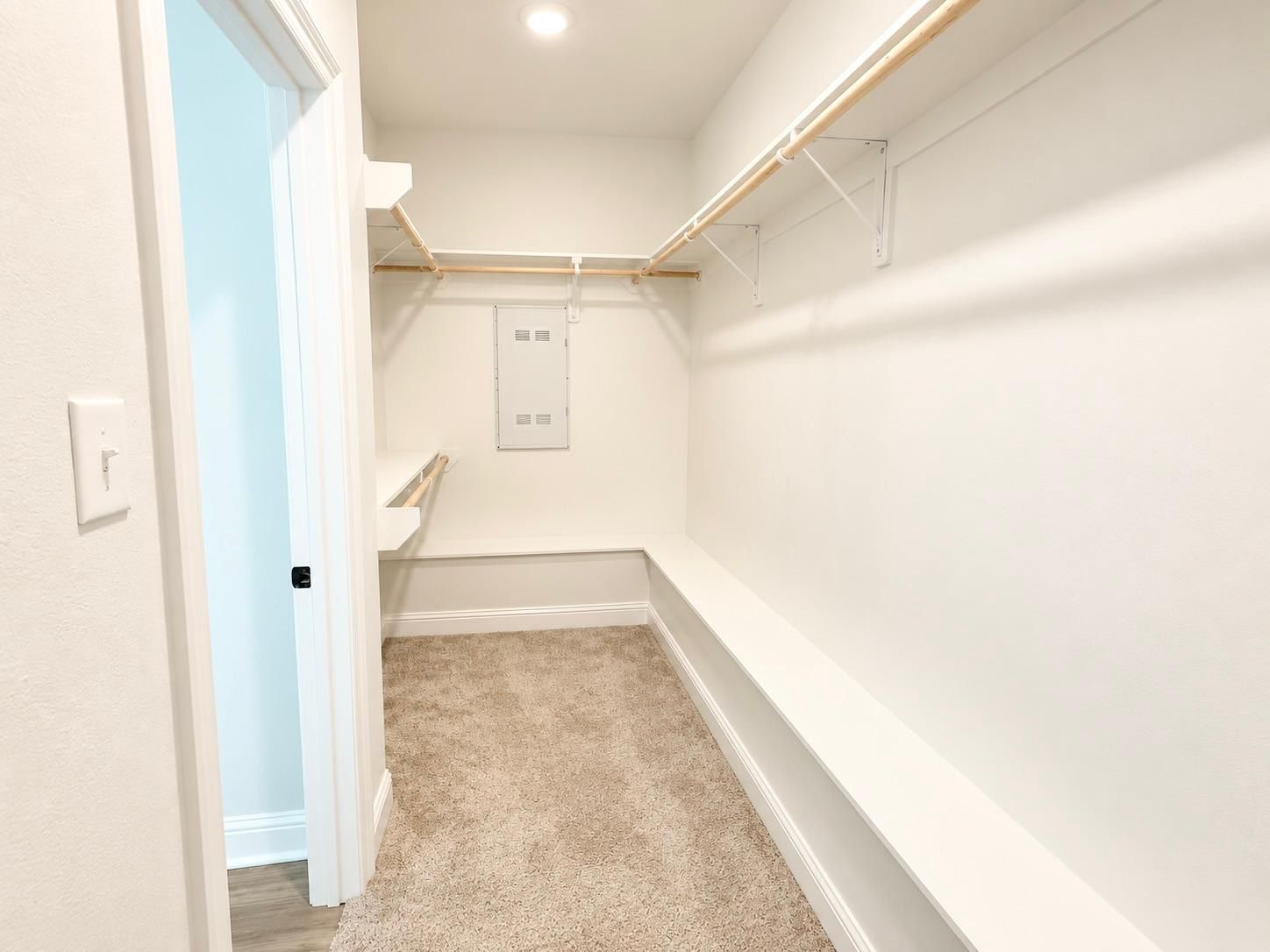 A narrow hallway with a carpeted floor, white walls, and a door leading to another room.