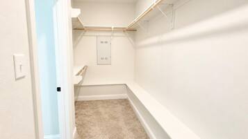 A narrow hallway with a carpeted floor, white walls, and a door leading to another room.